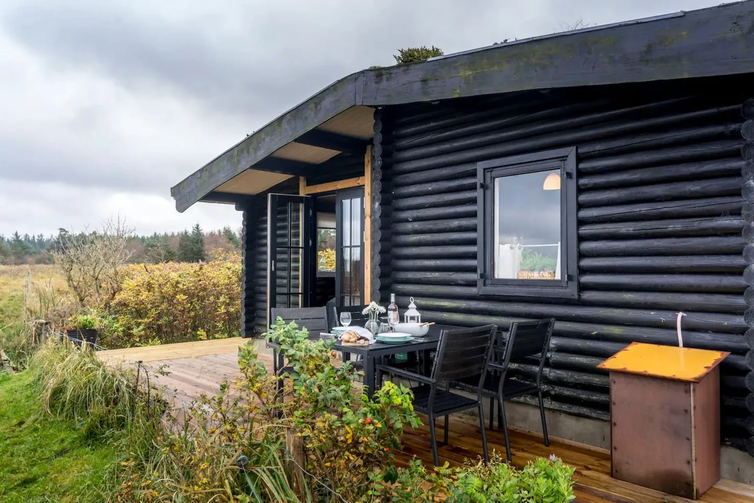 Holzterrasse am Blockhaus mit gedecktem Tisch